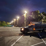 LUX LED Flood Light illuminating a parking lot with bright, efficient commercial-grade outdoor lighting at night.